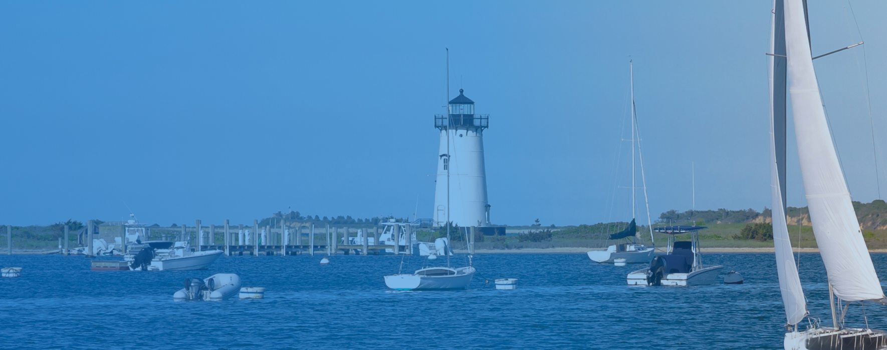 Lighthouse near shore filled with boats
